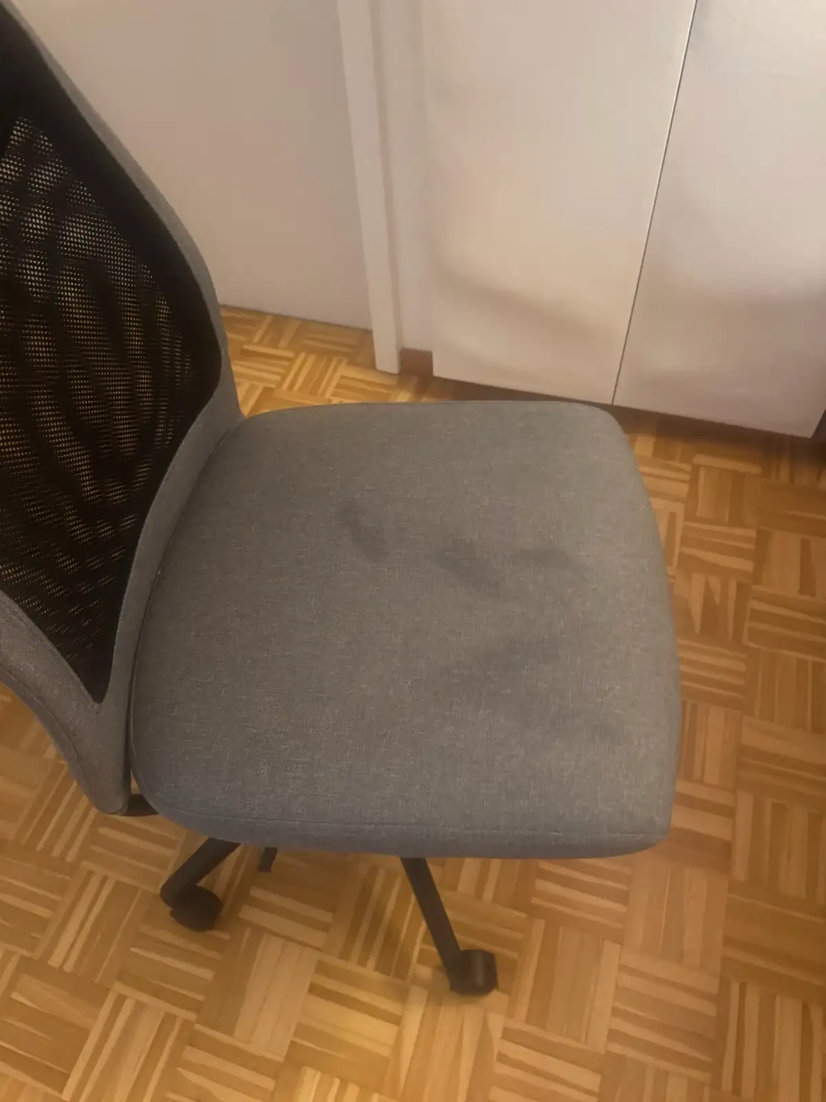 Bürostuhl-Sitzfläche mit Fleck von Körpercreme vor der Polsterreinigung